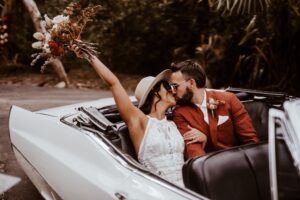 Happy couple posing in 67 Caddy after their wedding on the Central Coast NSW
