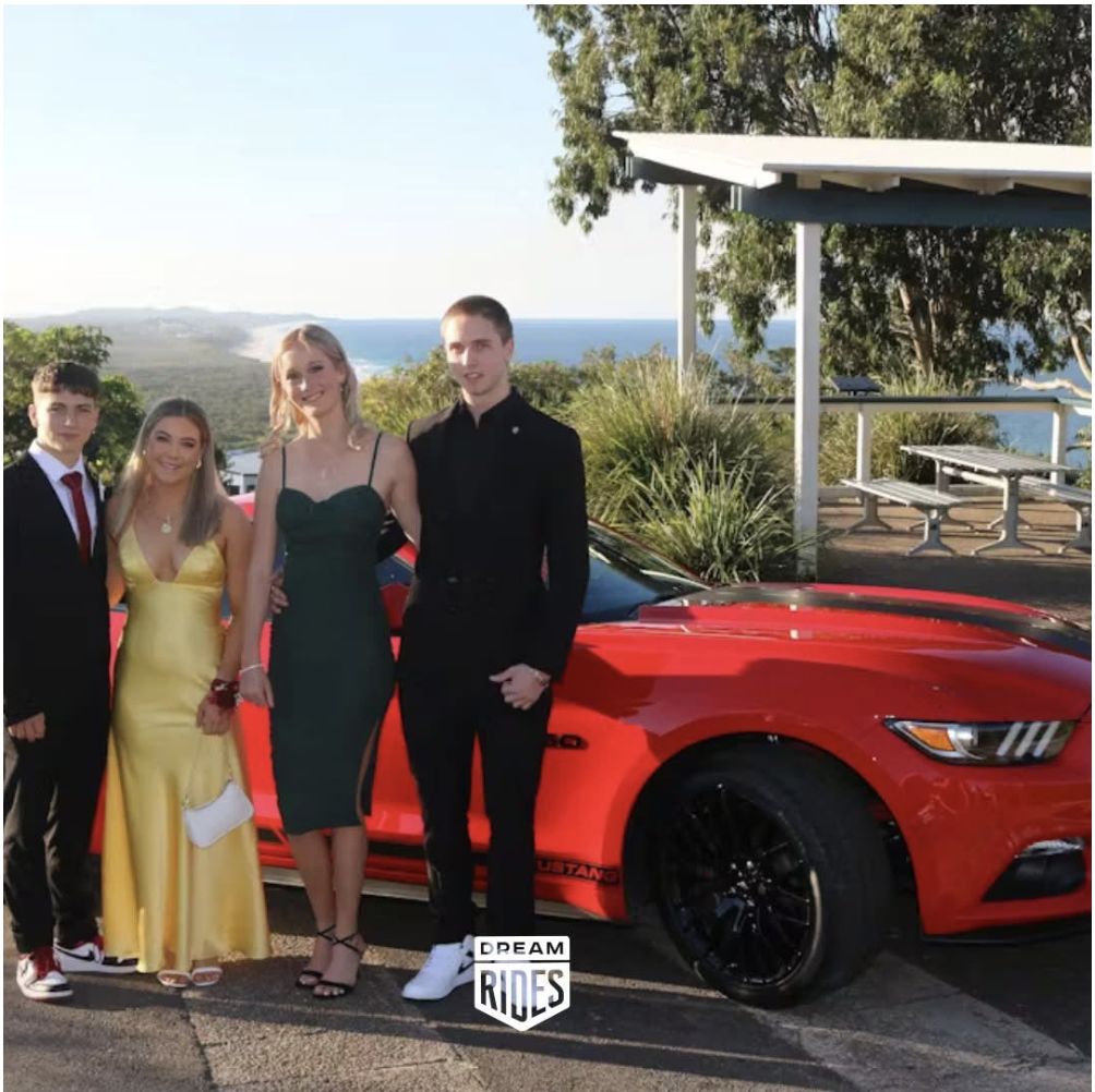 Red Ford Mustang formal car hire Sydney with students posing before arrival