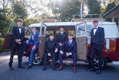 School formal boys in suits posing with 1967 VW Kombi Jacqueline surf bus hire Brisbane